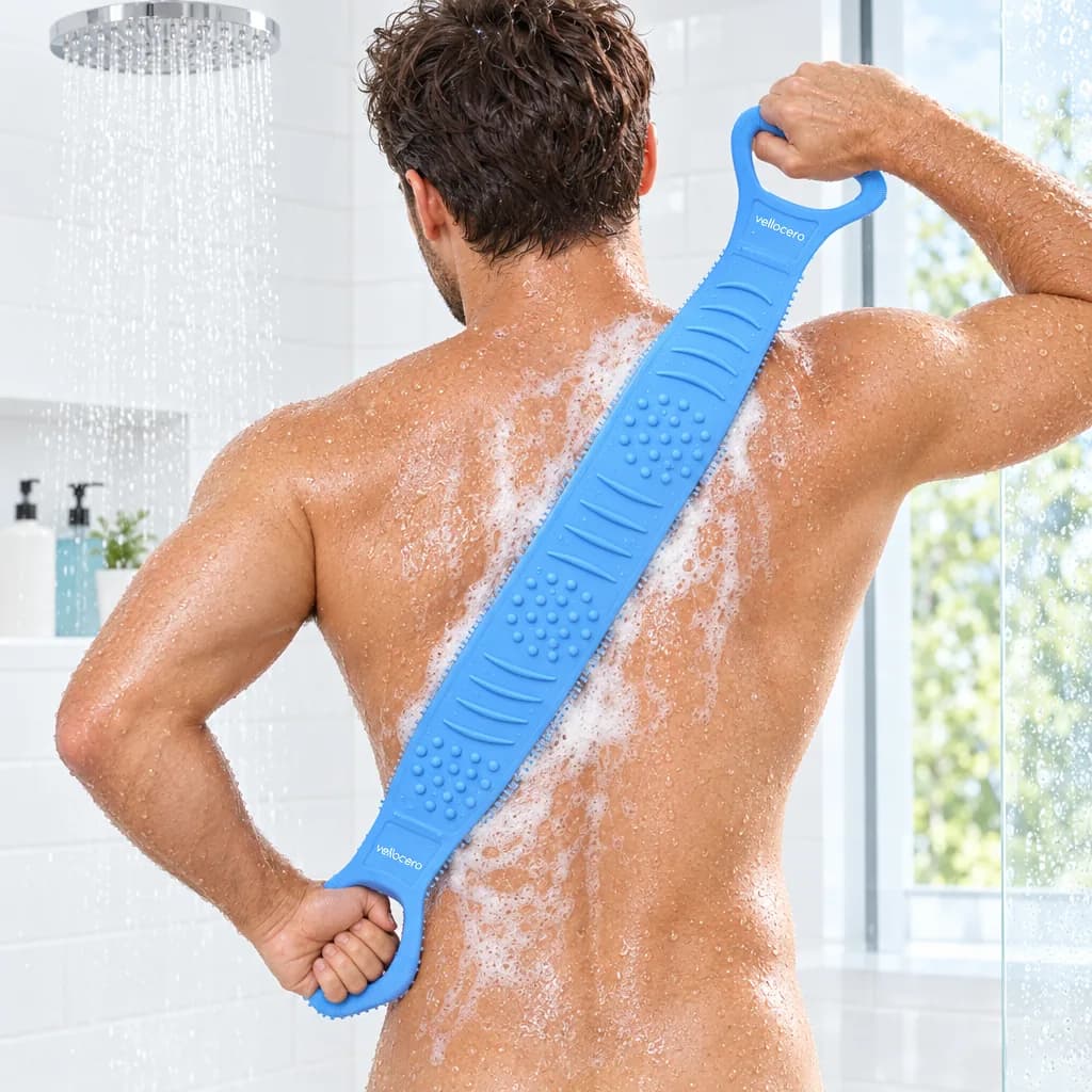 Hombre en la ducha frotándose toda la espalda con espuma, sujetando el cepillo por las dos asas